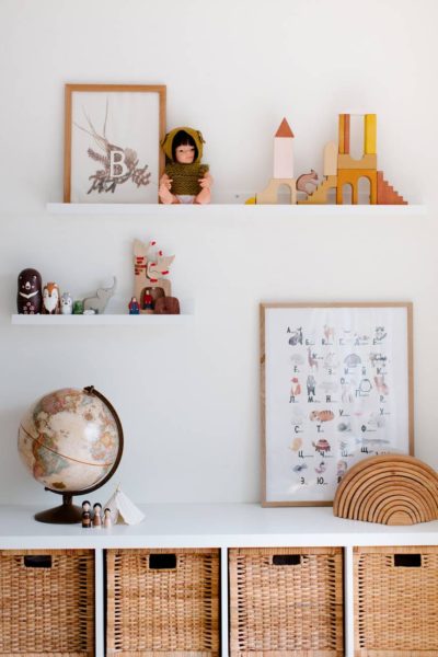 vintage glove on cabinet with toys and paintings on shelves at home